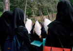 Junge Studentinnen in der vorgeschriebenen Kleiderordnung „hejab“, schwarzer lager Mantel und Magna-e (Kaputze), essen Zuckerwatte in der Freizeit, Teheran, Iran 2004  © Ulla Kimmig